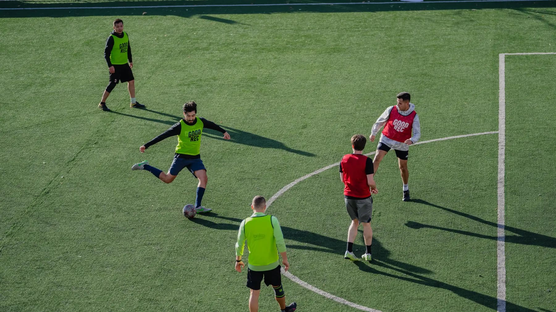 Five players mid-game on turf during a GoodRec pickup soccer game